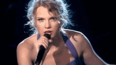 taylor swift is singing into a microphone on a stage .