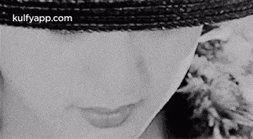 a black and white photo of a woman 's face with a hat .