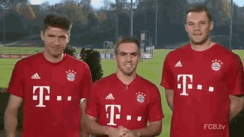 three men are standing next to each other wearing red t-mobile shirts .