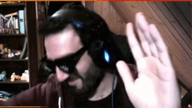 a man wearing sunglasses and headphones is waving