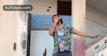 a man is standing in front of a building with his arms outstretched while drinking from a cup .