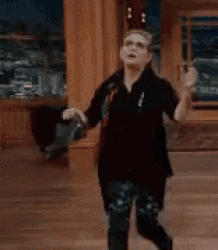 a woman is standing on a wooden floor holding a purse and dancing .