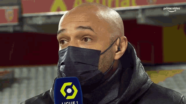 a man wearing a face mask and a microphone that says ligue 1 on it