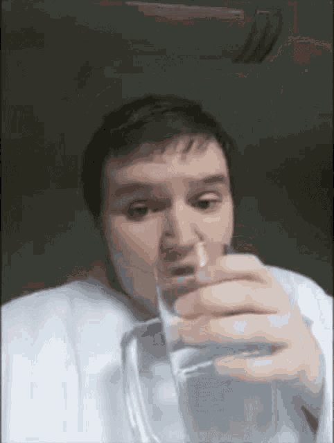 a man is drinking a glass of water in a dark room .