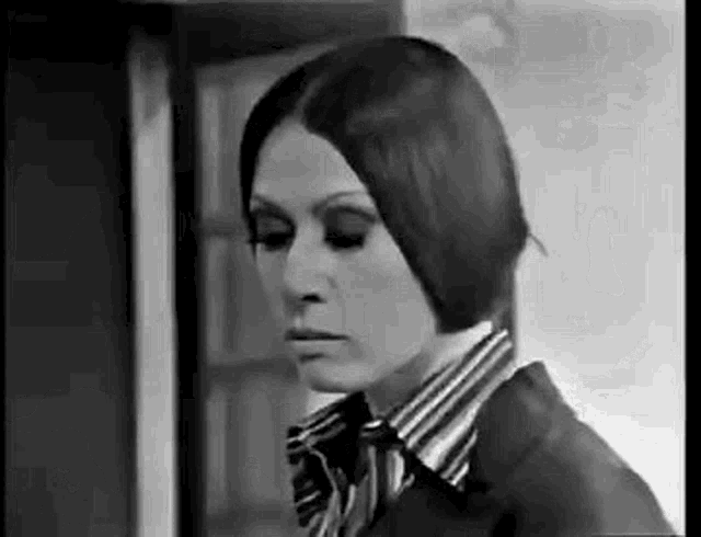a black and white photo of a woman in a striped shirt and jacket .
