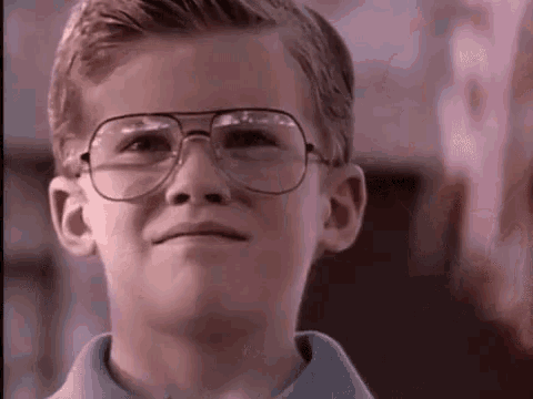 a young boy wearing glasses and a blue shirt is making a funny face .