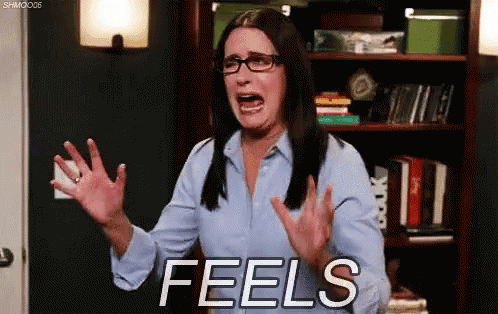 a woman with glasses and a blue shirt is screaming with the word feels behind her