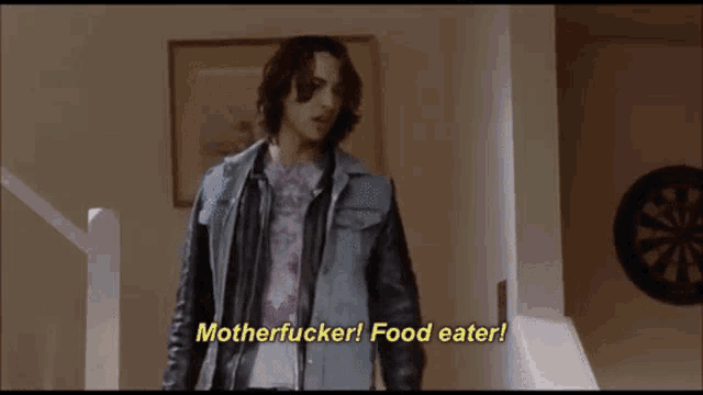 a man in a leather jacket is standing in front of a dart board and says motherfucker food eater .