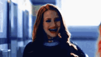 a woman is smiling in a hallway and wearing a choker .
