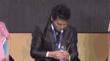 a man in a suit and tie is smoking a cigarette .