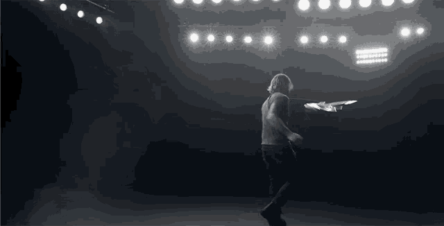 a man is dancing in a dark room with a lot of lights behind him
