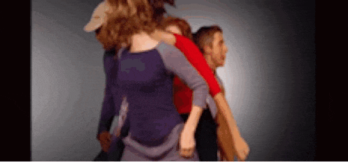 a group of people are standing in a circle with their arms around each other .