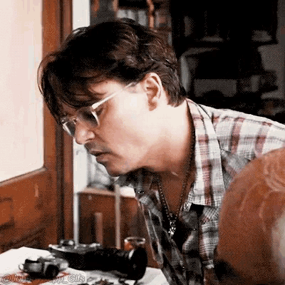 a man wearing glasses is looking down at something