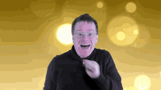 a man wearing glasses and a black sweater is smiling