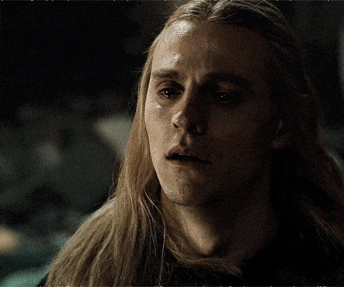 a close up of a man with long blonde hair making a sad face