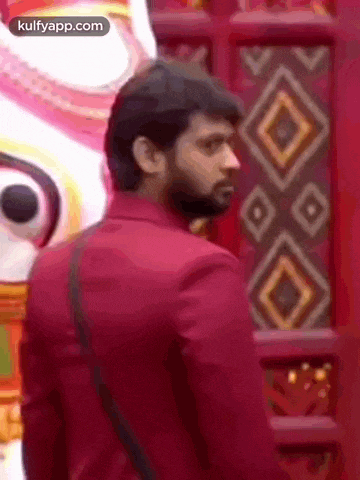 a man in a red suit is standing in front of a wall with a pattern .
