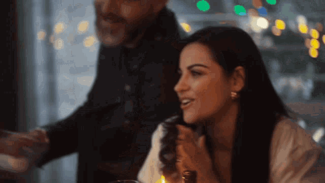 a man and a woman are sitting at a table with a candle in front of them