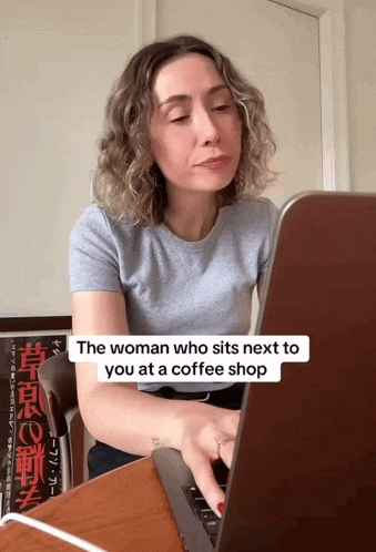 a woman sits at a desk with a laptop and a sign that says the woman who sits next to you