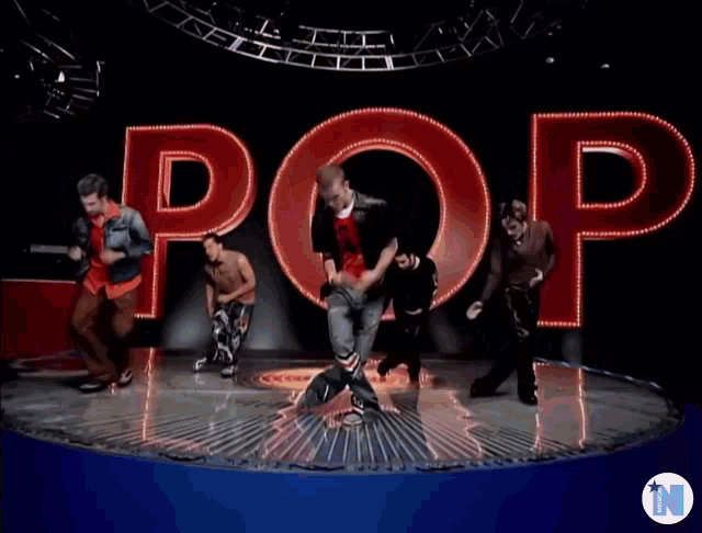 a group of men are dancing on a stage with the word pop in the background