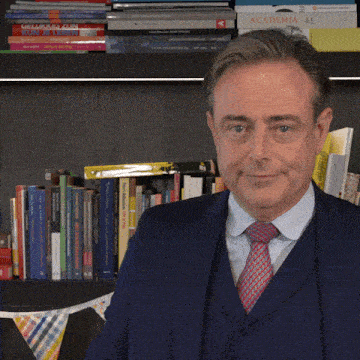 a man in a suit and tie is standing in front of a bookshelf with a book called academia on it