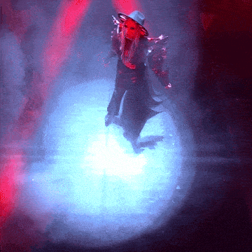 a man in a hat is standing in a dark room with a blue light behind him