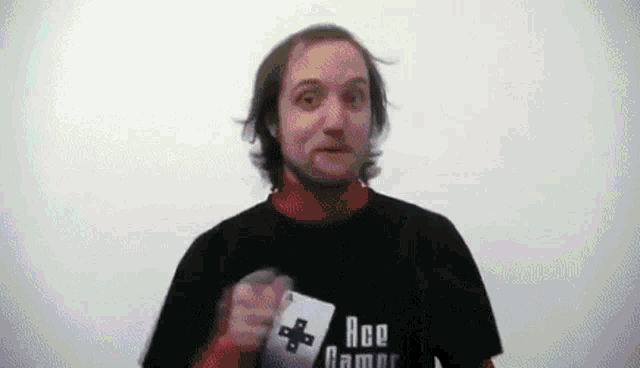 a man wearing a black t-shirt that says ace games is holding a game controller