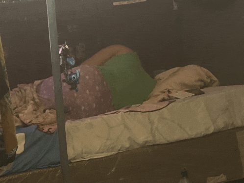 a person laying on a bed in a dark room with a sign on the wall that says ' emergency exit '