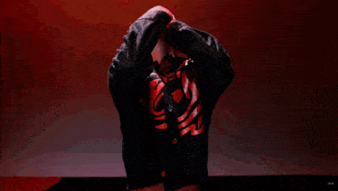 a man in a red shirt and red pants is standing with his arms behind his head