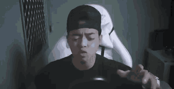 a man in a baseball cap is sitting in a chair with his hand on his head and the caption jangan sok ngartis deh .