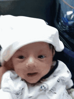 a baby wearing a white hat is making a funny face