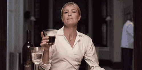 a woman is sitting at a table with a glass of wine .