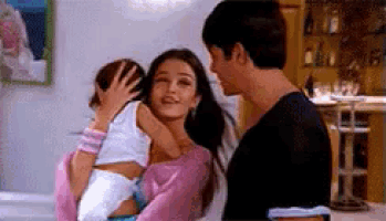 a woman is holding a baby in her arms while a man kisses her .