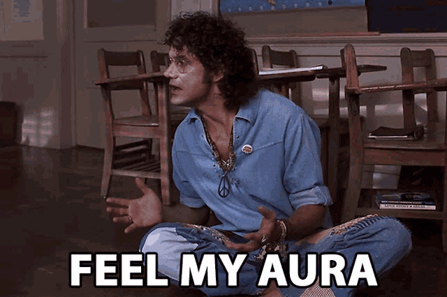 a man sits on the floor in a classroom with the words feel my aura behind him