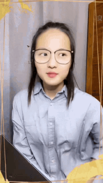 a woman wearing glasses and a blue shirt looks to the side