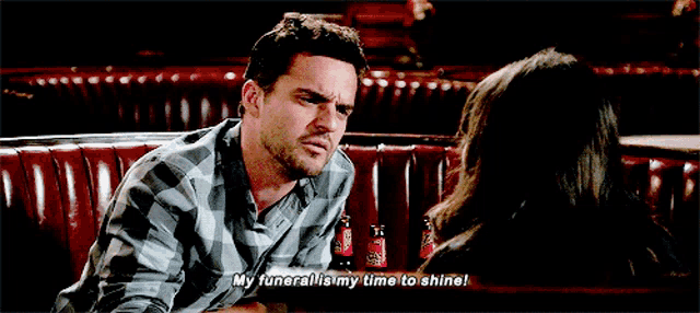 a man in a plaid shirt is talking to a woman in a diner and says " my funeral is my time to shine