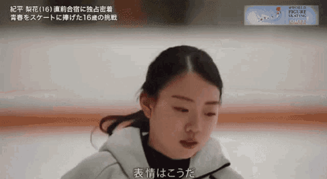 a woman is sitting on a ice rink with chinese writing on the bottom right corner .
