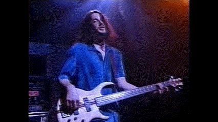 a man with long hair is playing a bass guitar on stage