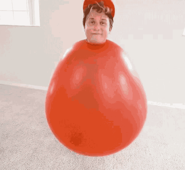 a man is standing inside of a red balloon