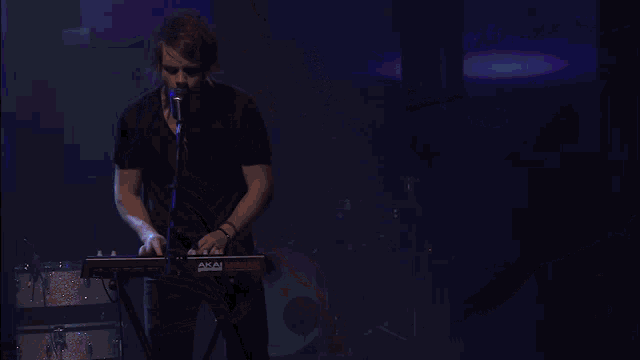a man singing into a microphone with a blue screen behind him