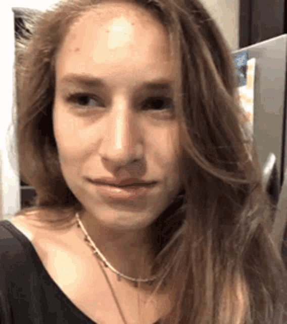 a close up of a woman 's face with long hair and a necklace