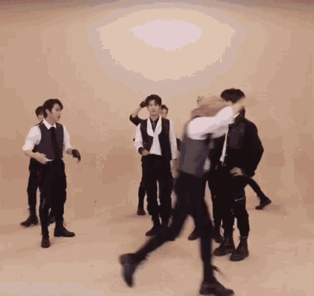a group of men are dancing in a room with a tan background