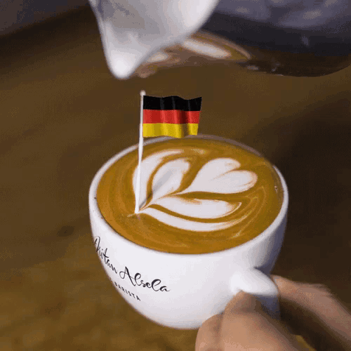 a cup of coffee with a small german flag on top of it