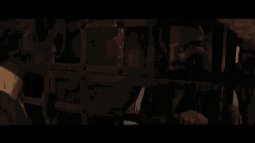 a man is behind bars in a dark room looking at another man behind bars
