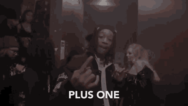 a man in a black jacket is giving the middle finger in a crowd of people .