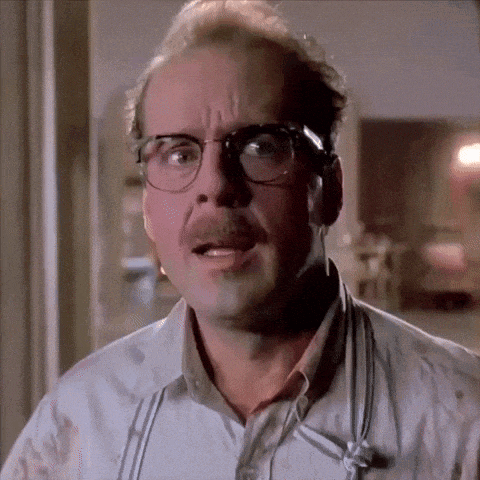 a man wearing glasses and suspenders looks surprised
