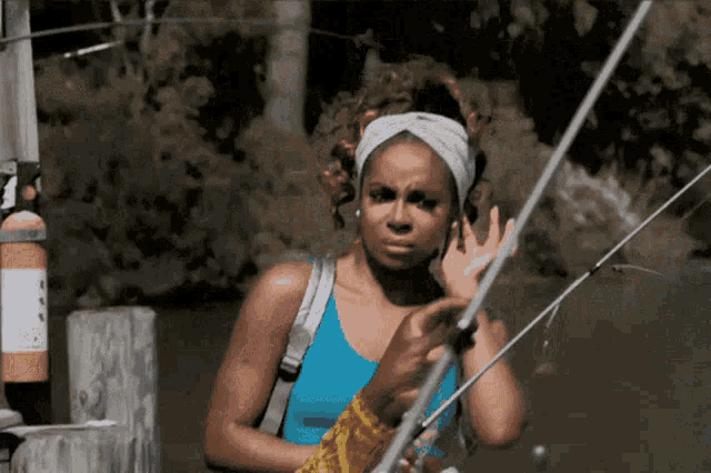 a woman in a blue tank top holds a fishing pole