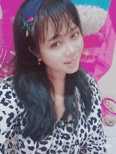 a woman in a leopard print shirt is smiling in front of a pink background that says vivavideo