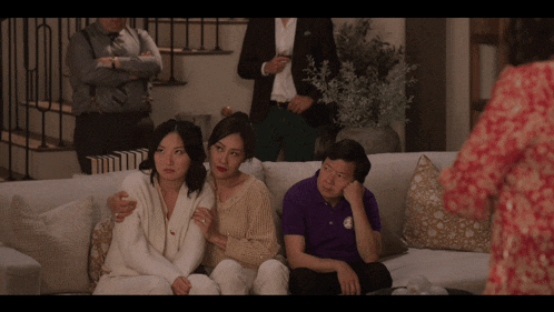 a group of people are sitting on a couch and one of them is wearing a purple polo shirt