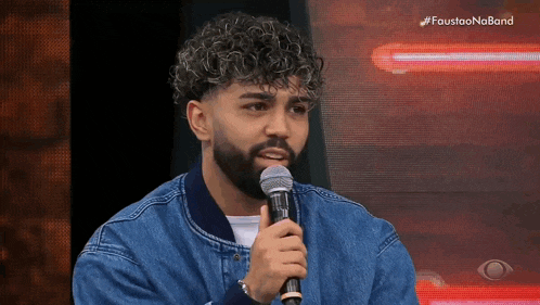 a man with a beard is holding a microphone in front of a screen that says faustao no band