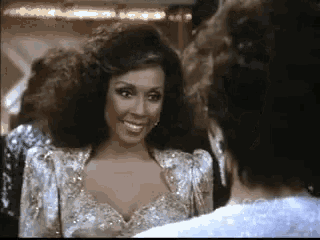 a woman in a sequined dress is smiling at another woman